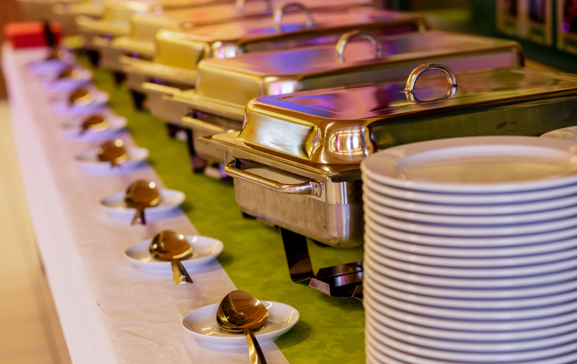 A buffet table with plates , utensils , and trays of food.