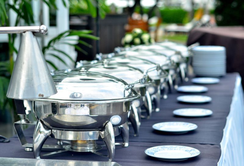 A long buffet table with plates and pots on it.