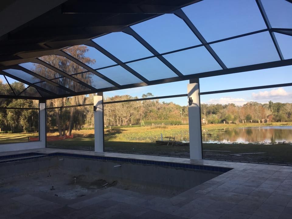 A screened in area with a view of a lake and trees