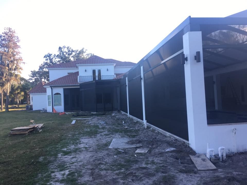 A large white house with a black screened in porch in front of it.