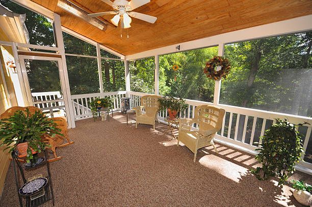 A screened in porch with chairs and a ceiling fan