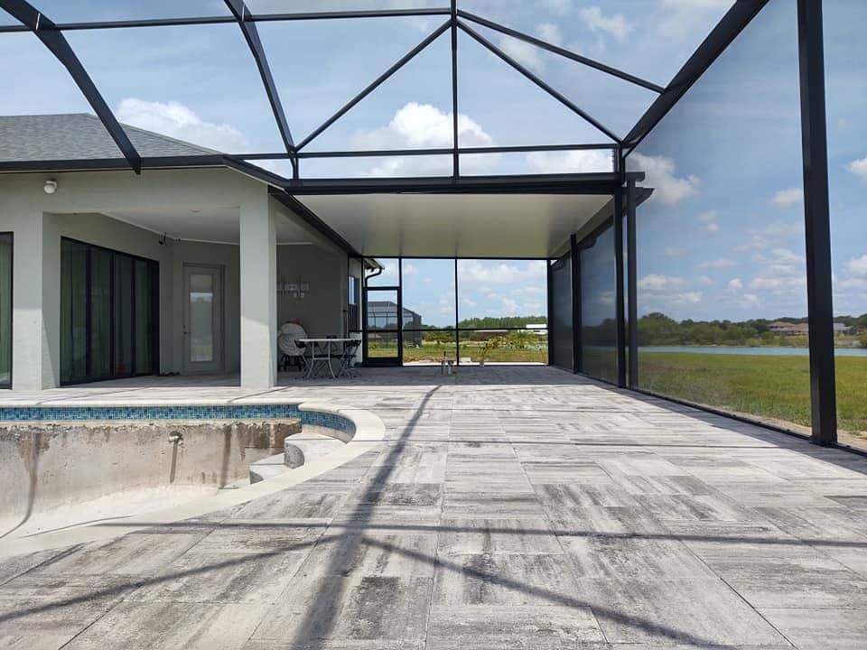 A screened in porch with a swimming pool in the background.