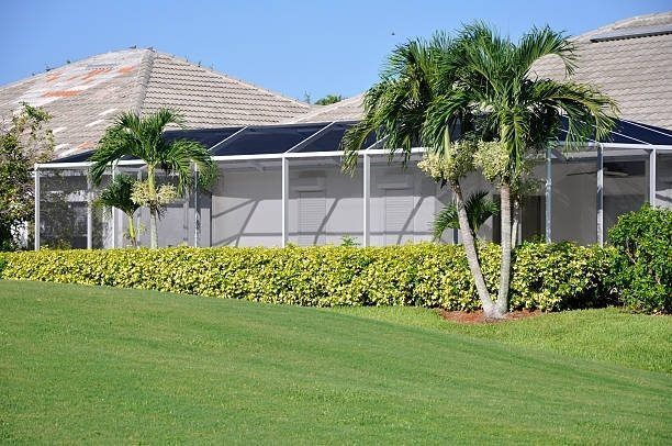 A house with a screened in porch and palm trees in front of it.