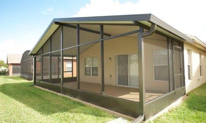 A screened in porch in the backyard of a house