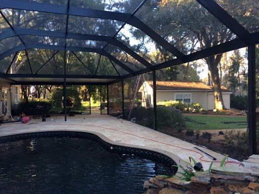 A screened in swimming pool with a house in the background