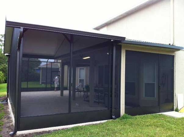 A screened in porch with a patio in the backyard of a house.
