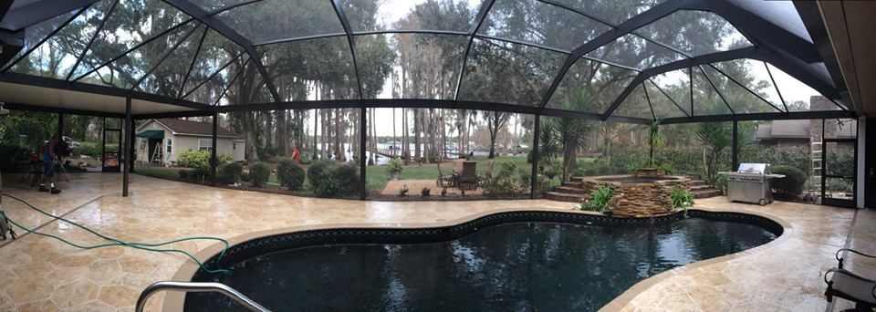 A large swimming pool in a screened in area with trees in the background.