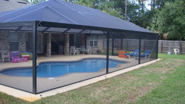 A screened in swimming pool with a canopy over it.
