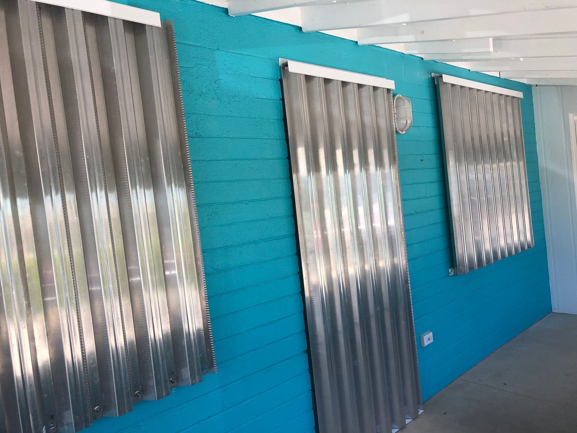 A hallway with blue walls and gray blinds on the windows.