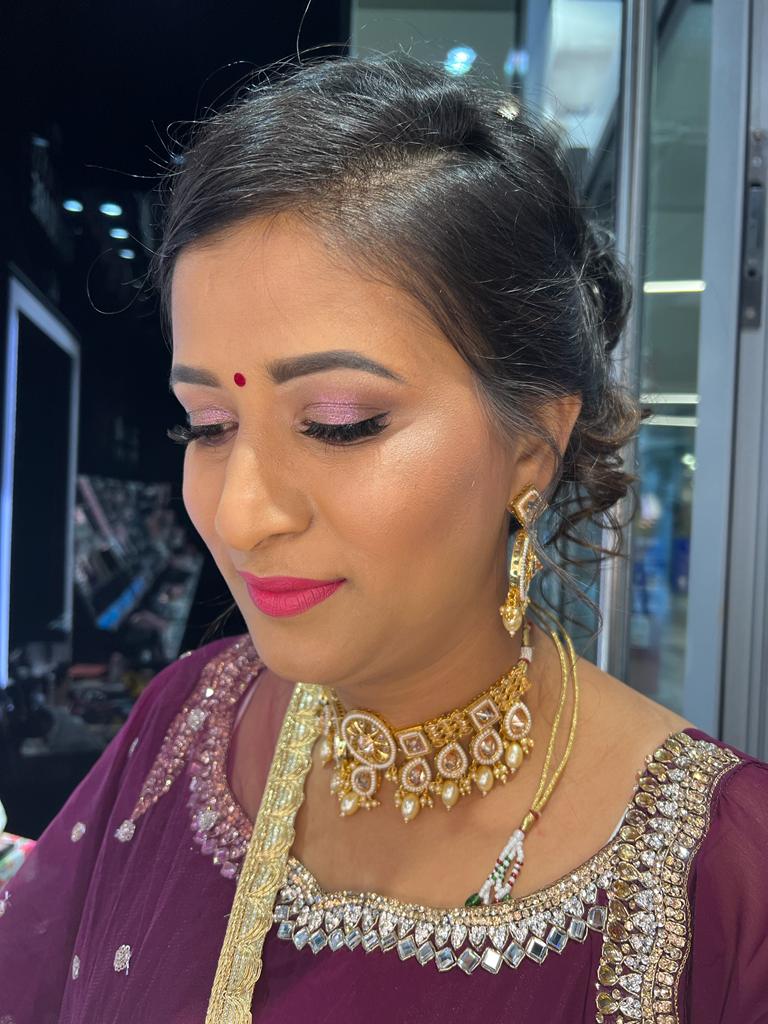 Donna indiana con make-up professionale, top viola con decorazioni e gioielli oro preziosi