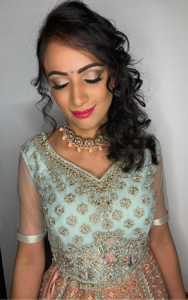 Donna indiana con make-up professionale, gioielli e top azzurro con ricami