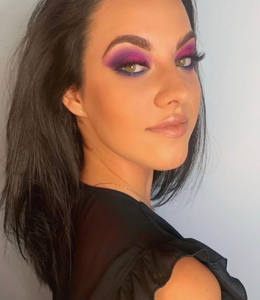 Donna con occhi verdi e ombretto viola, fucsia e blu