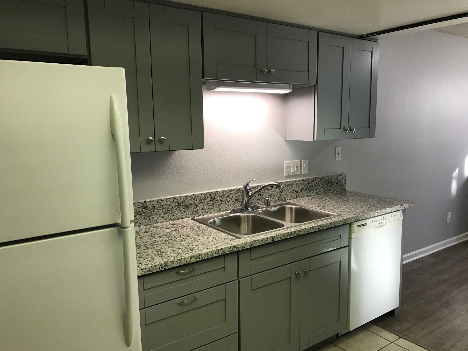 A kitchen with gray cabinets and a white refrigerator
