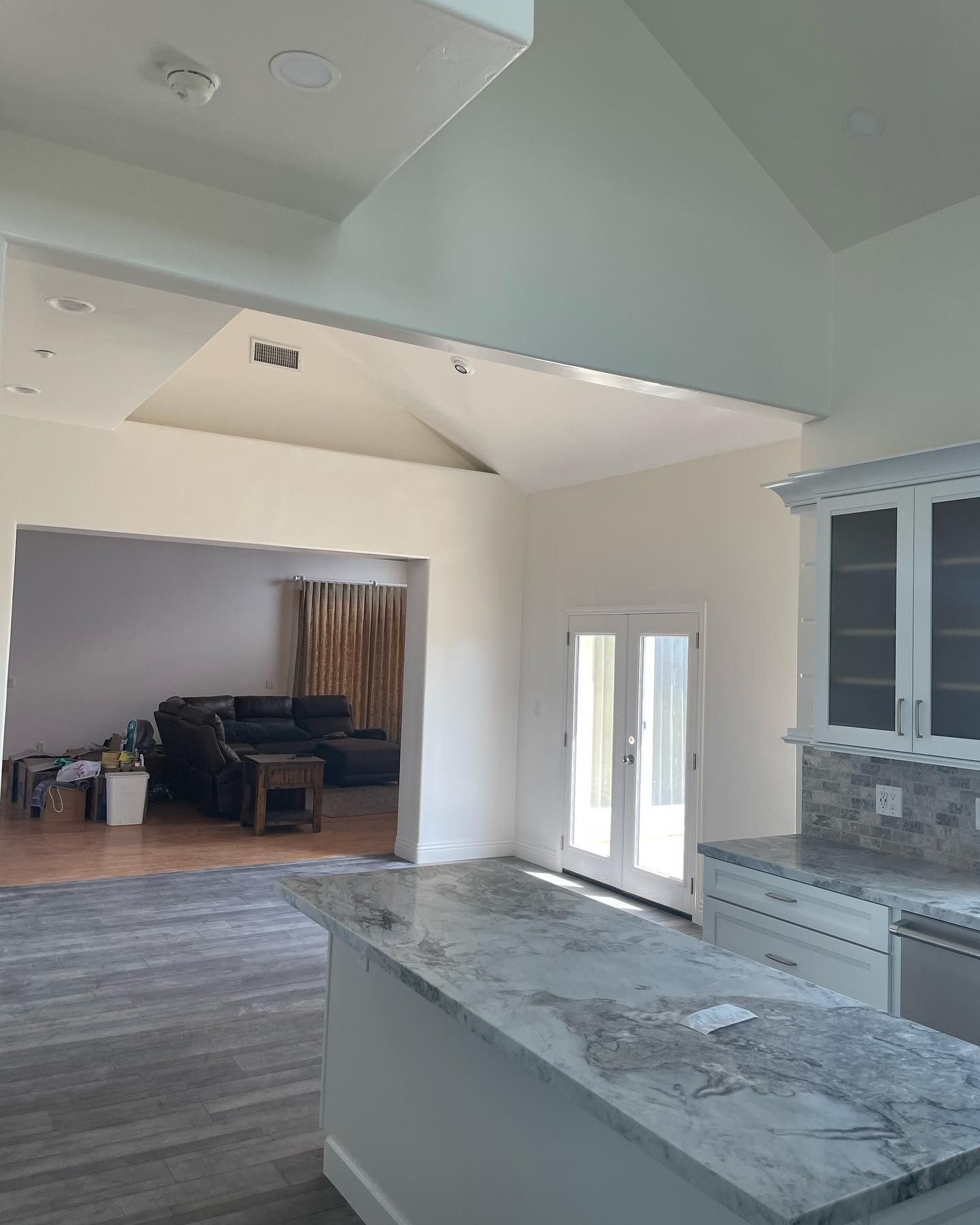 A kitchen with marble counter tops is open to a living room
