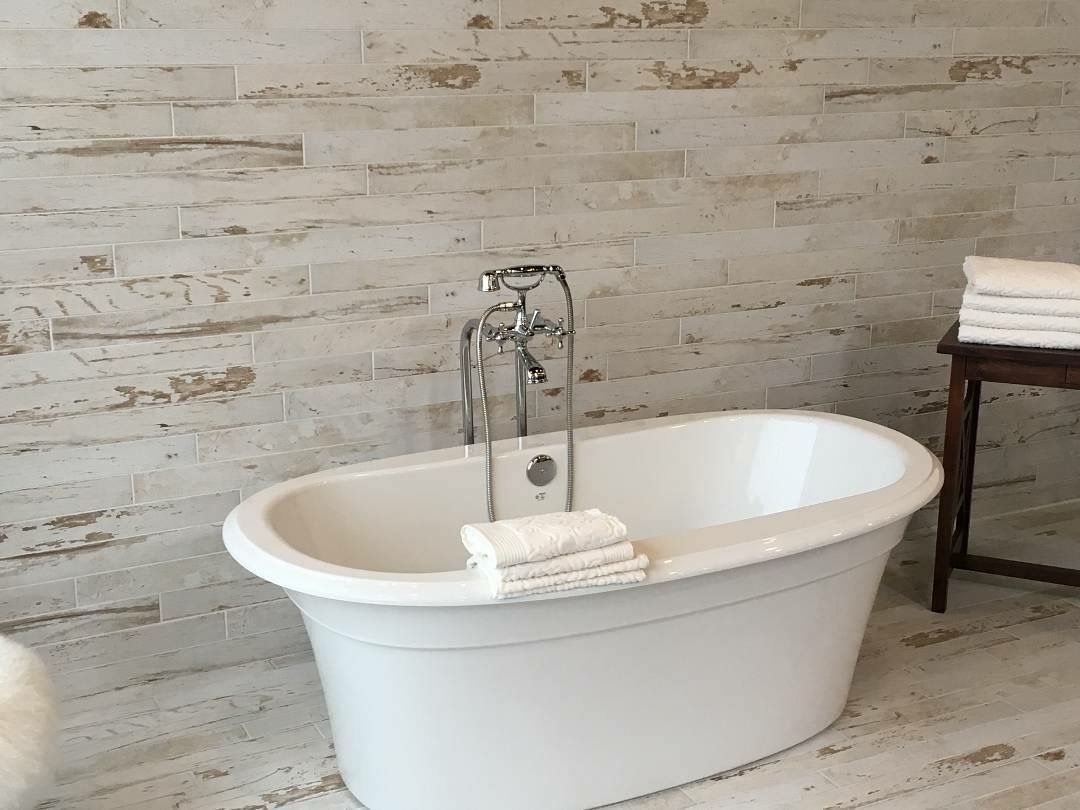 A white bathtub is sitting in a bathroom next to a stack of towels.