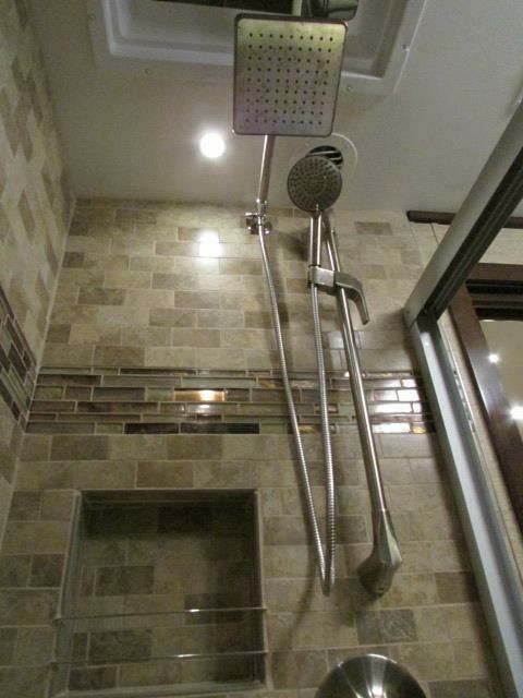 A shower head is hanging from the ceiling in a bathroom.