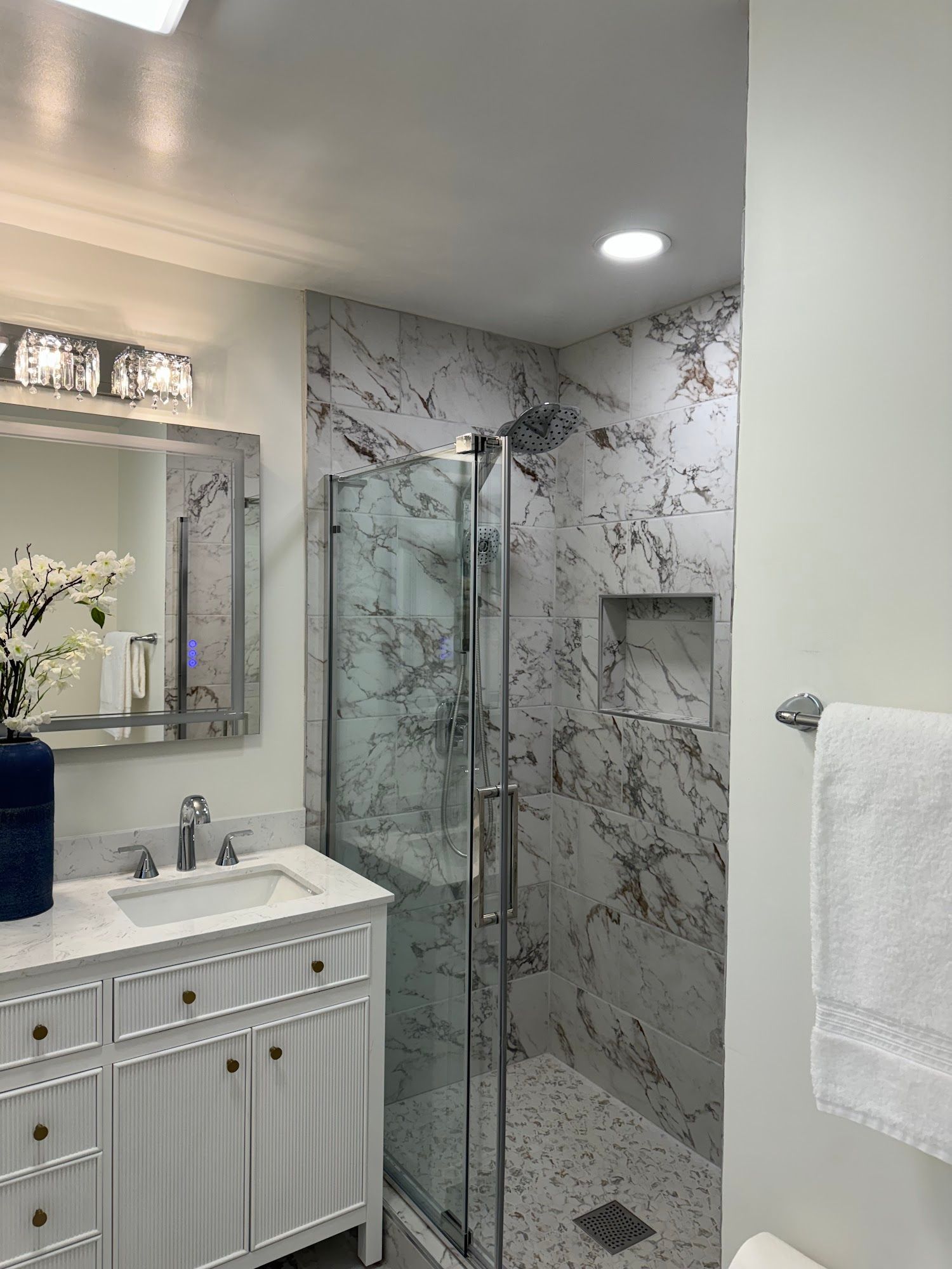 A bathroom with a sink , mirror , and walk in shower.