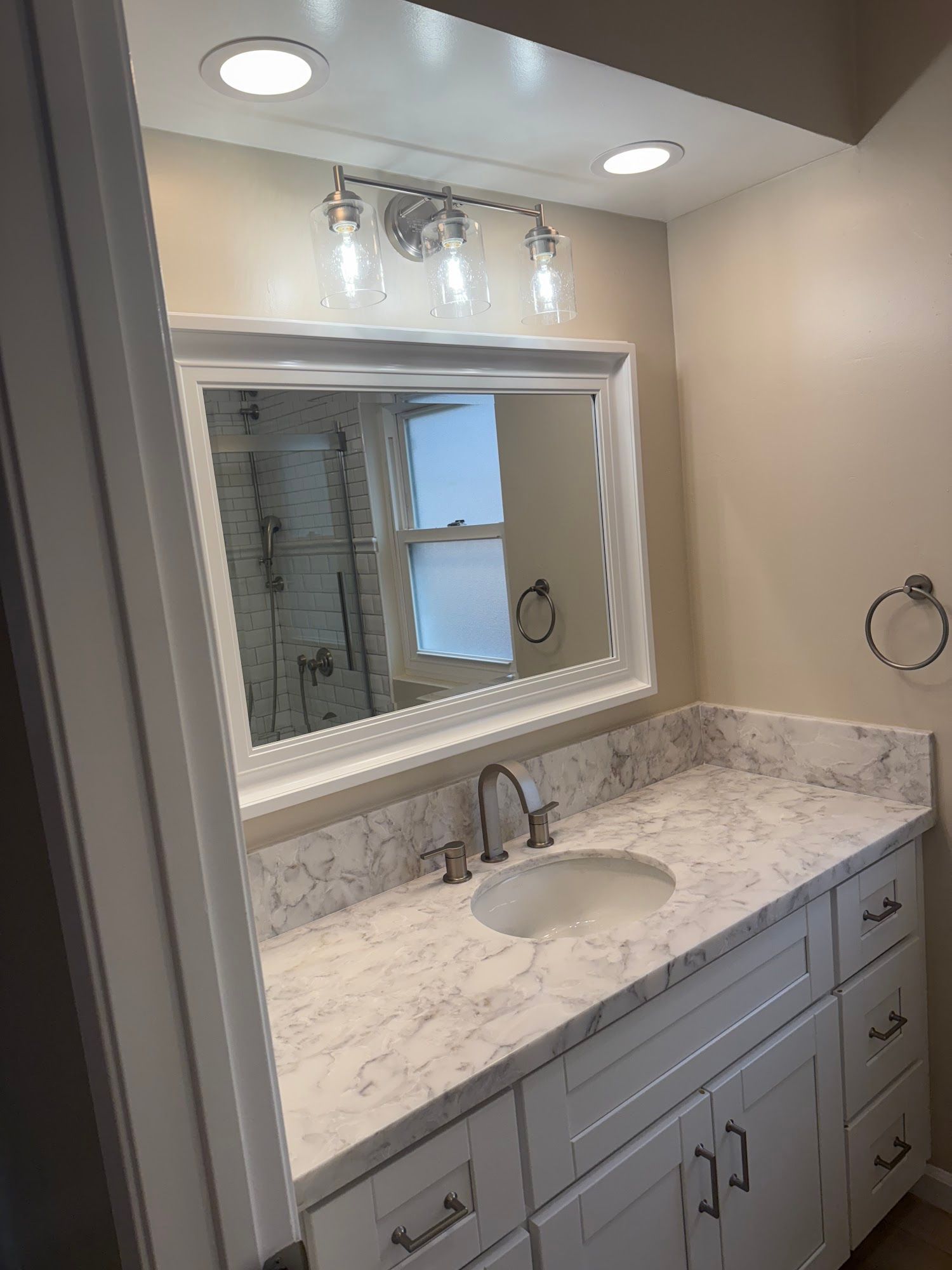 A bathroom with a sink , mirror and cabinets.