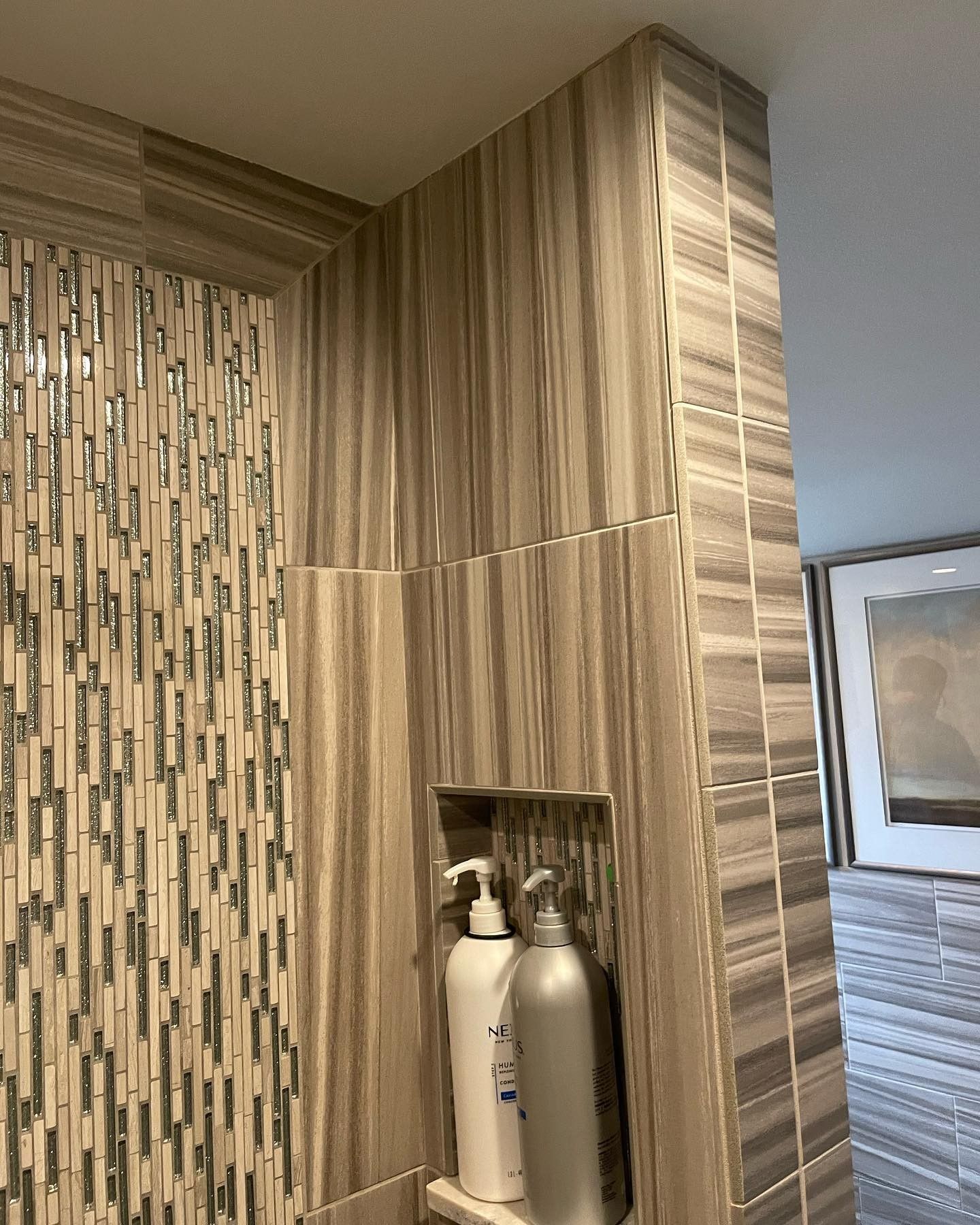 Two bottles of shampoo and conditioner are sitting in a niche in a bathroom.