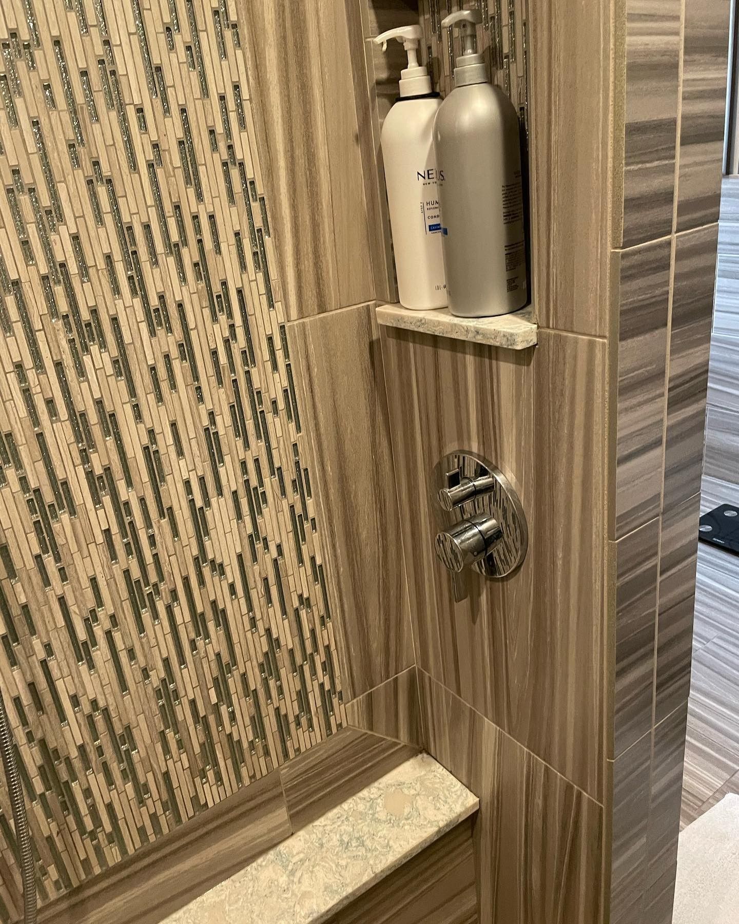 There are two bottles of shampoo and conditioner on a shelf in the shower.