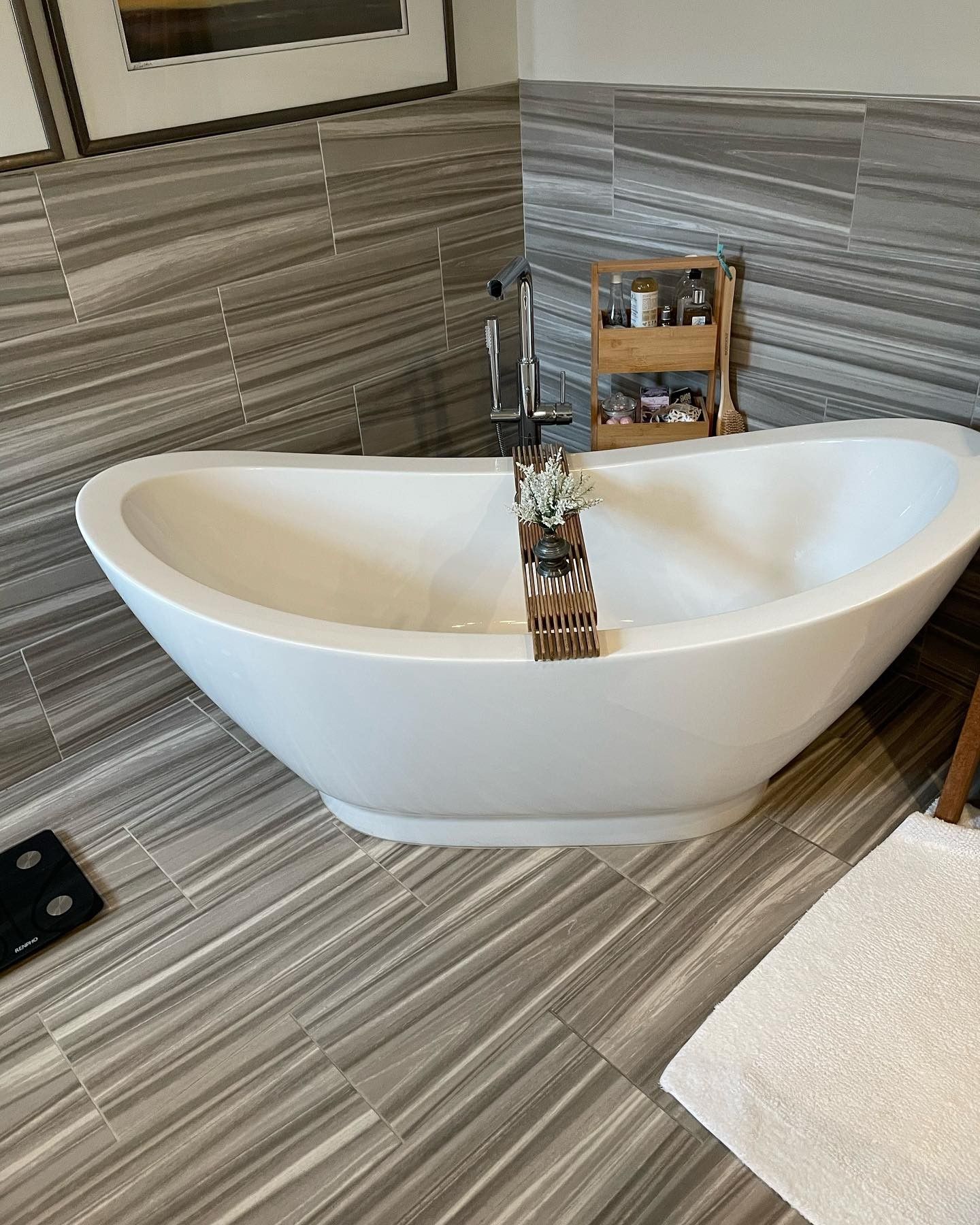A white bathtub is sitting on a tiled floor in a bathroom.
