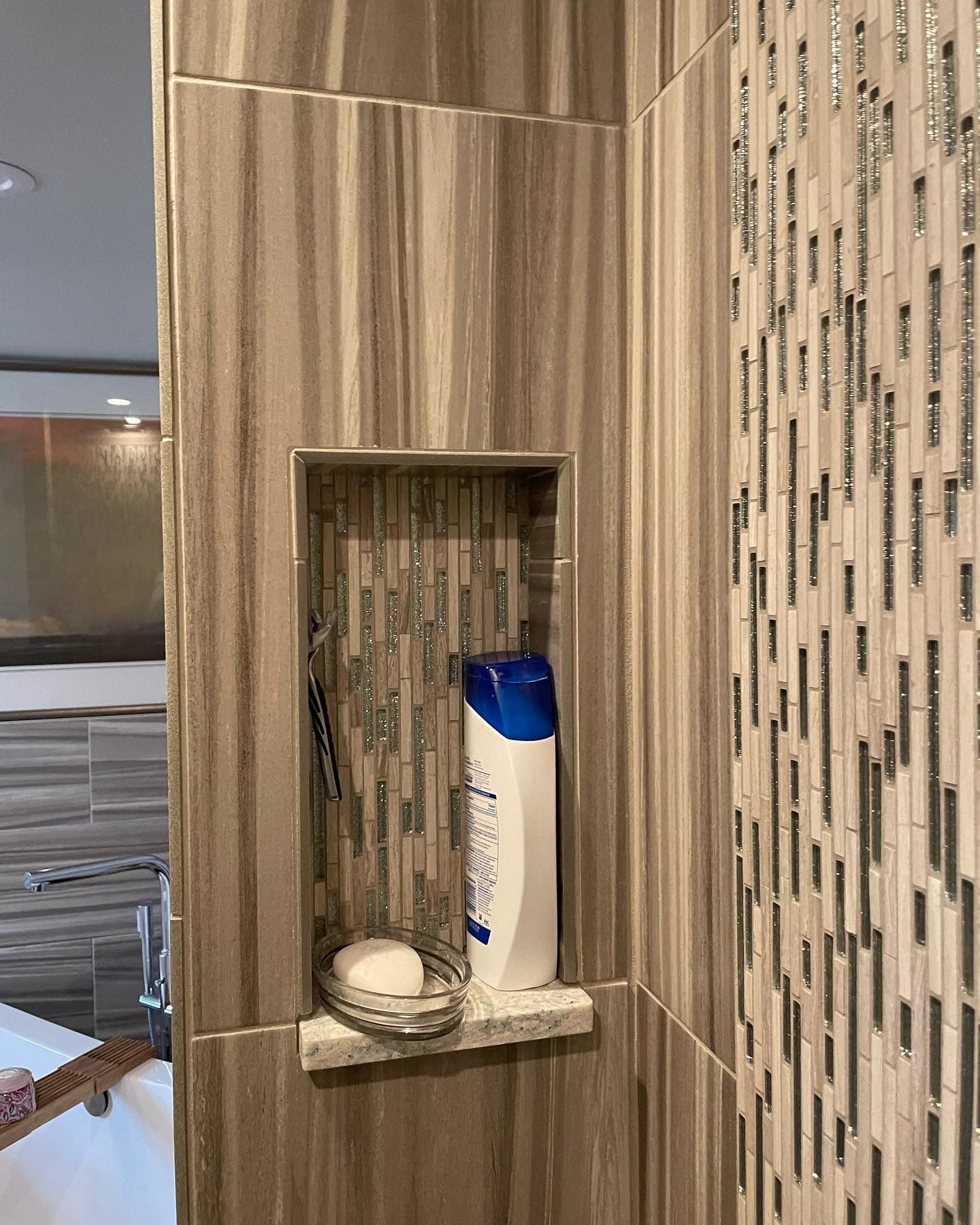 A shower niche with a bottle of shampoo and a soap dish.