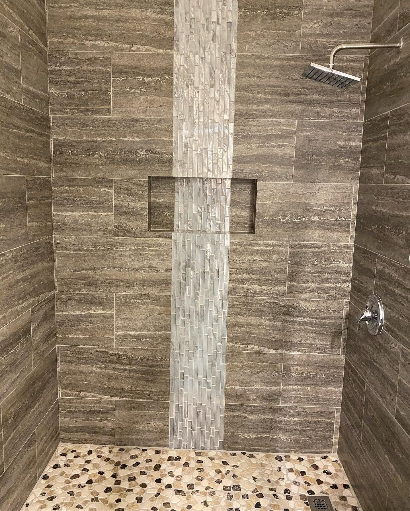 A walk in shower with tiled walls and a tiled floor.