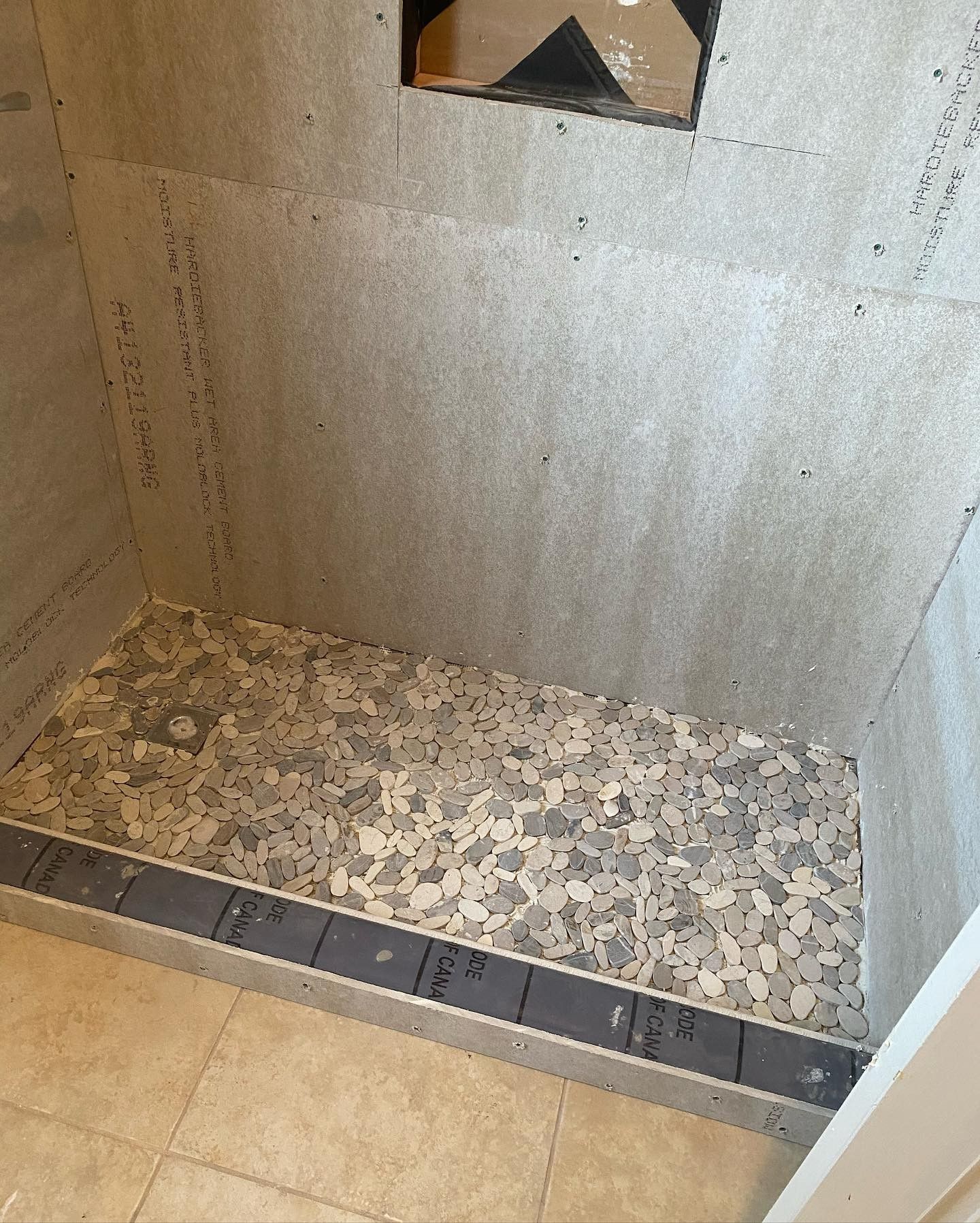 A shower stall with a tile floor and a gray border