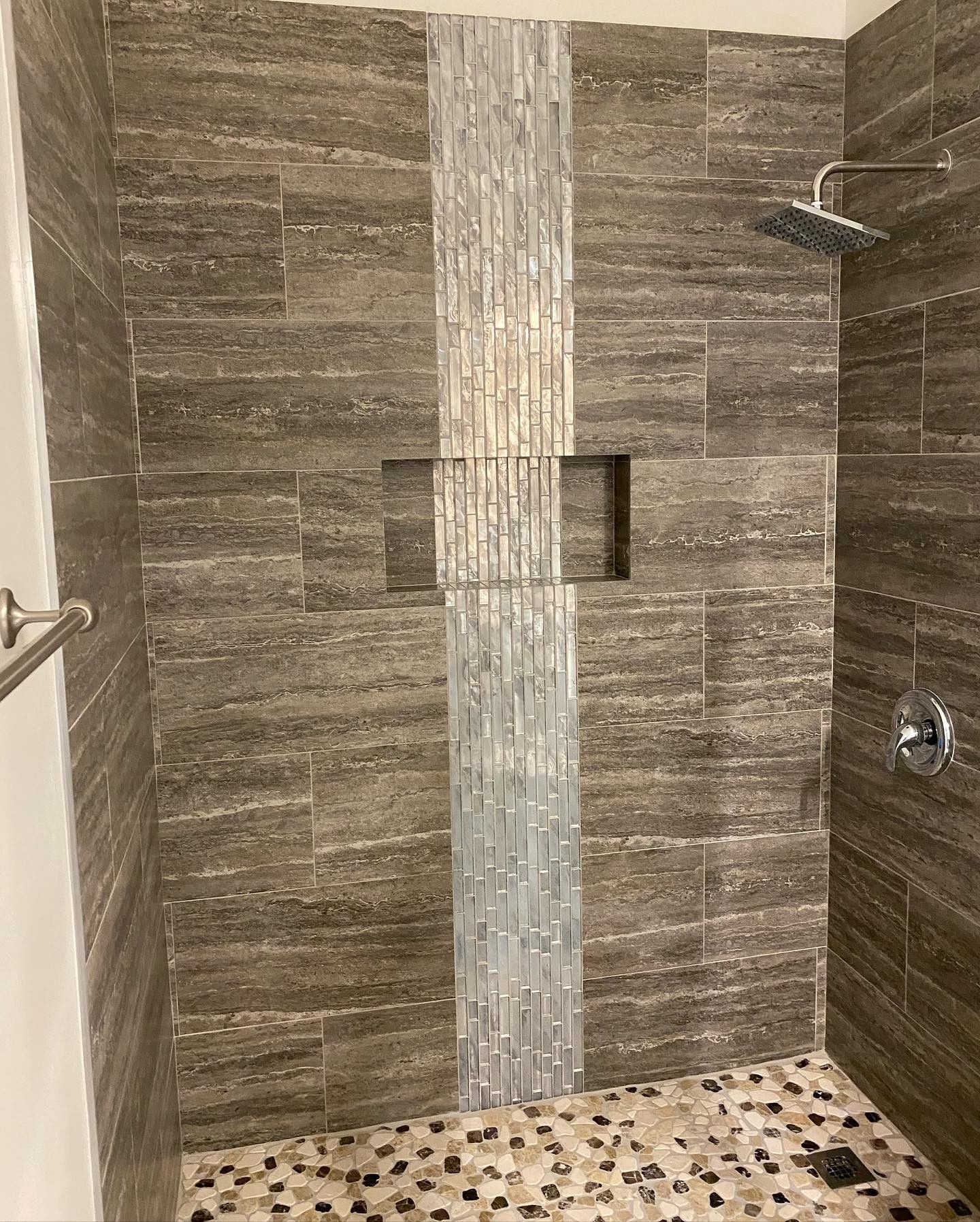 A walk in shower with a tiled wall and a shower head.