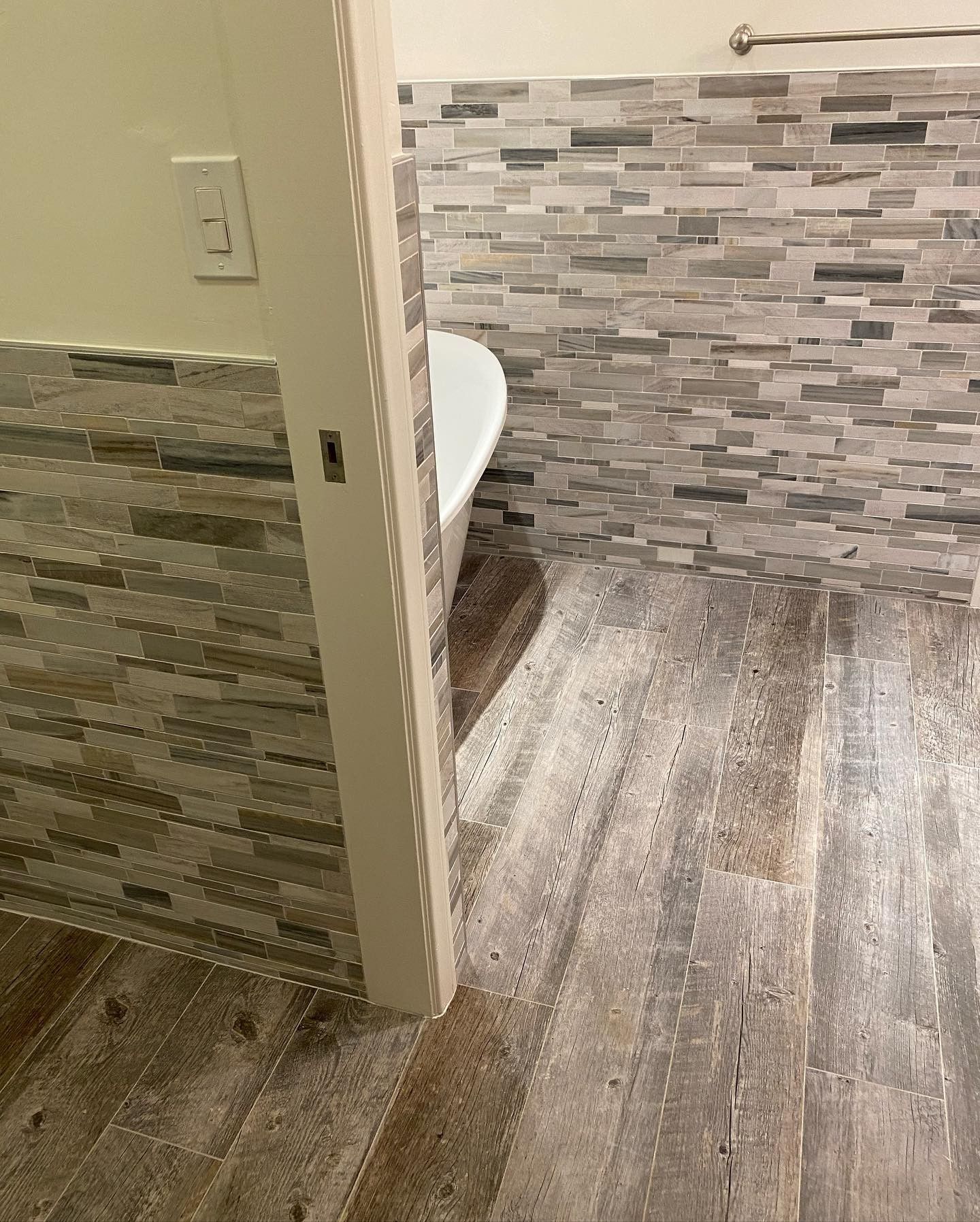 A bathroom with a bathtub and a tiled wall.