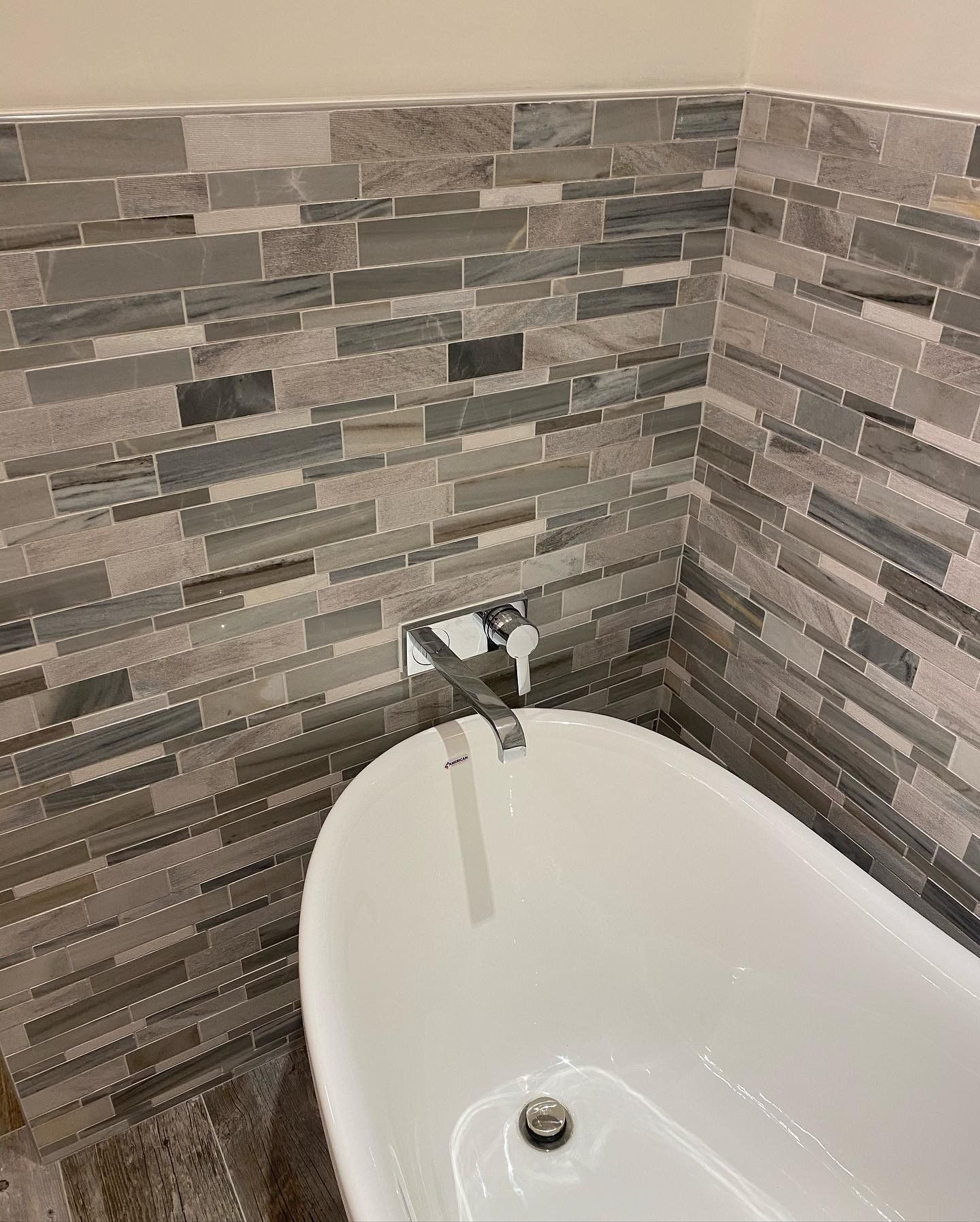 A bathtub in a bathroom next to a brick wall.