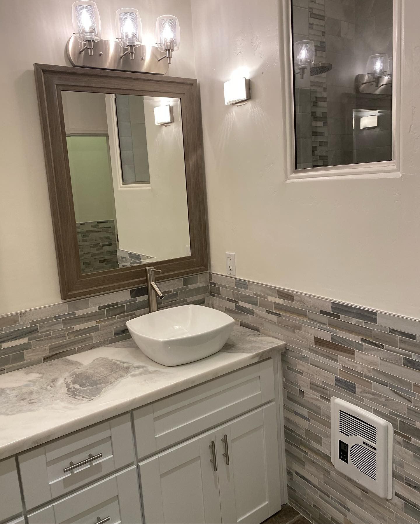 A bathroom with a sink , mirror and window.