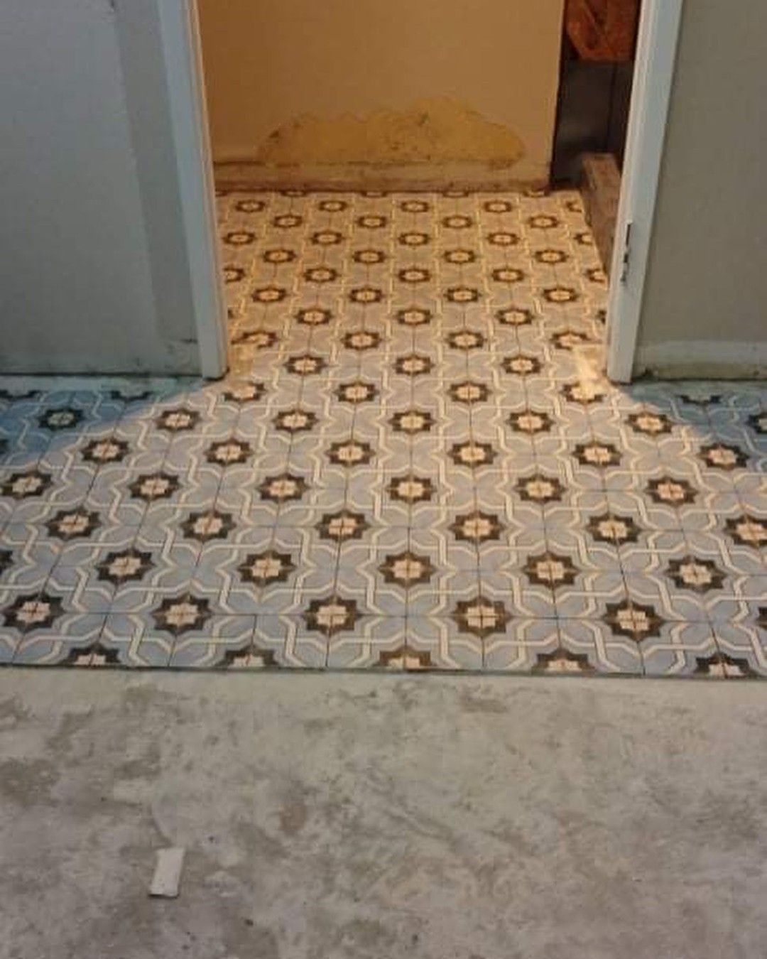 A doorway with a patterned tile floor leading to a bathroom.