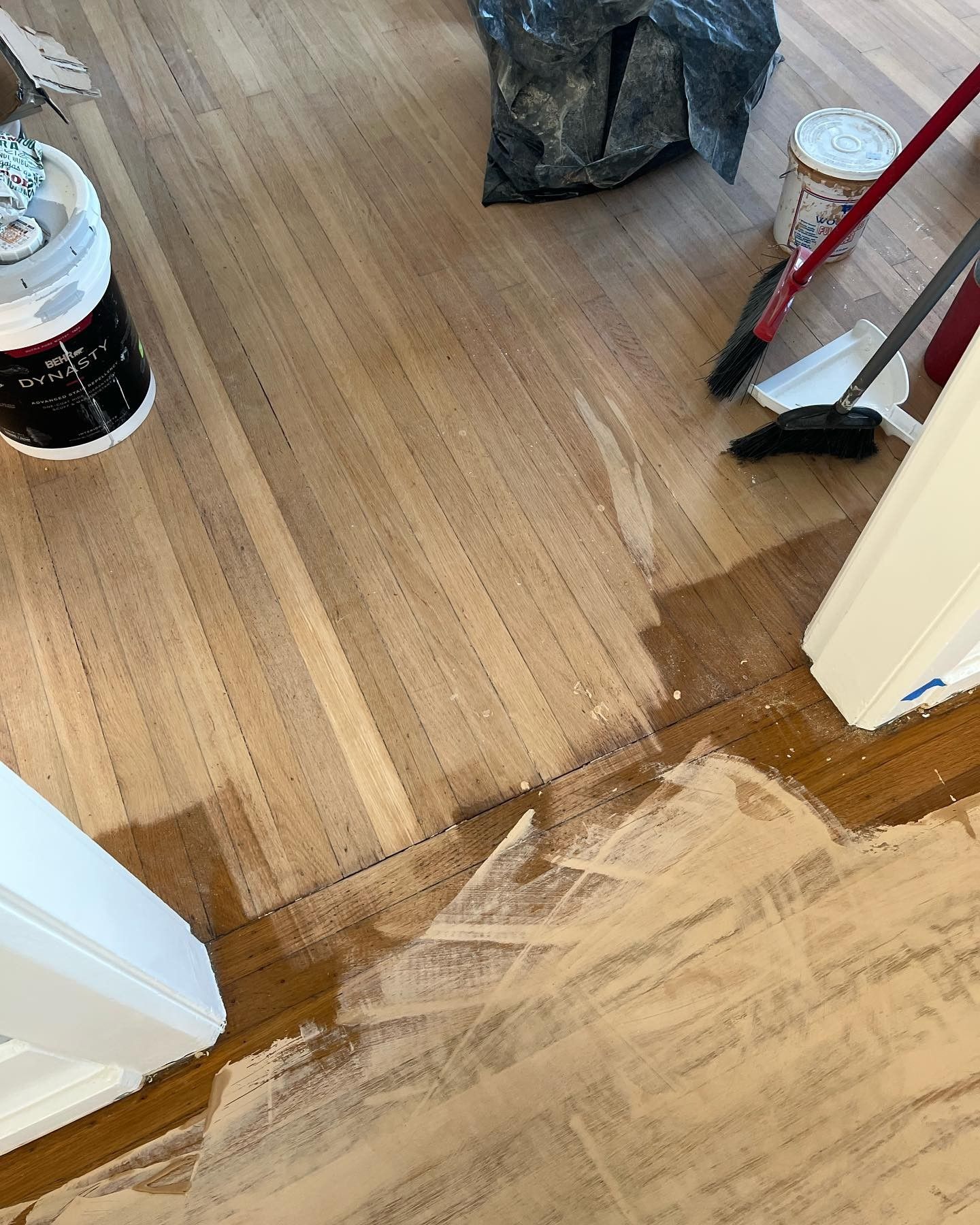 A wooden floor is being painted in a room.