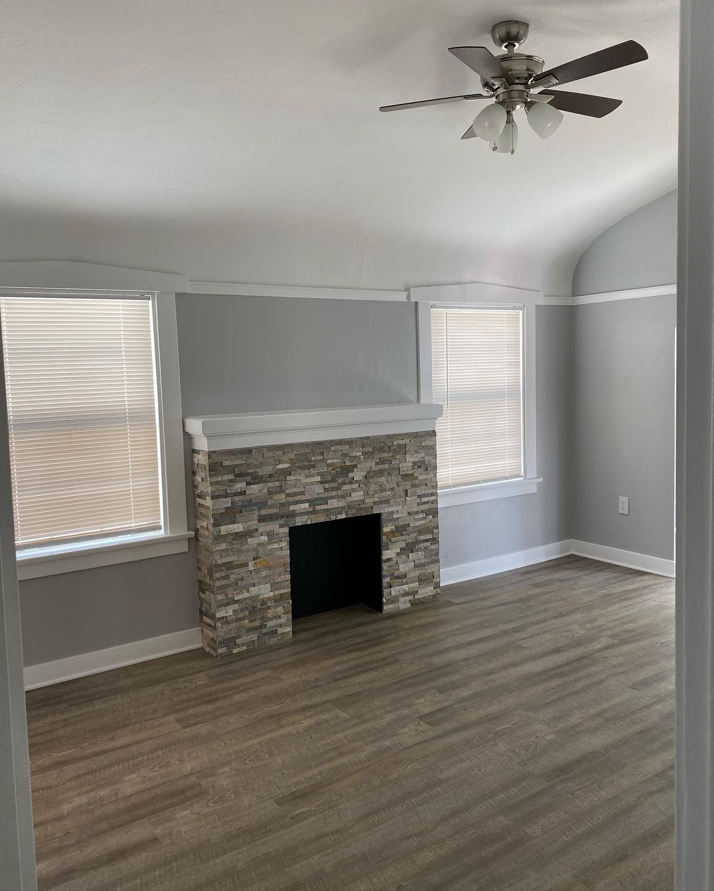 A living room with a fireplace and a ceiling fan.