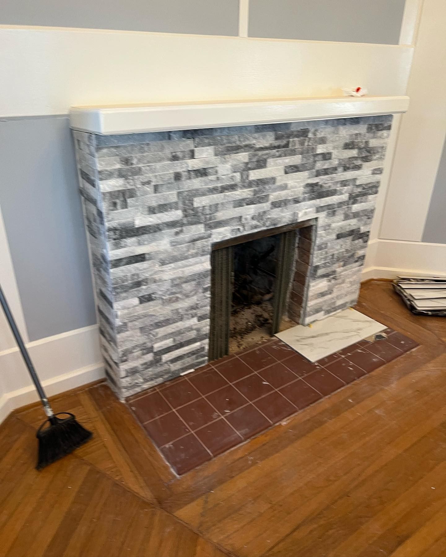 A fireplace in a living room with a broom on the floor.