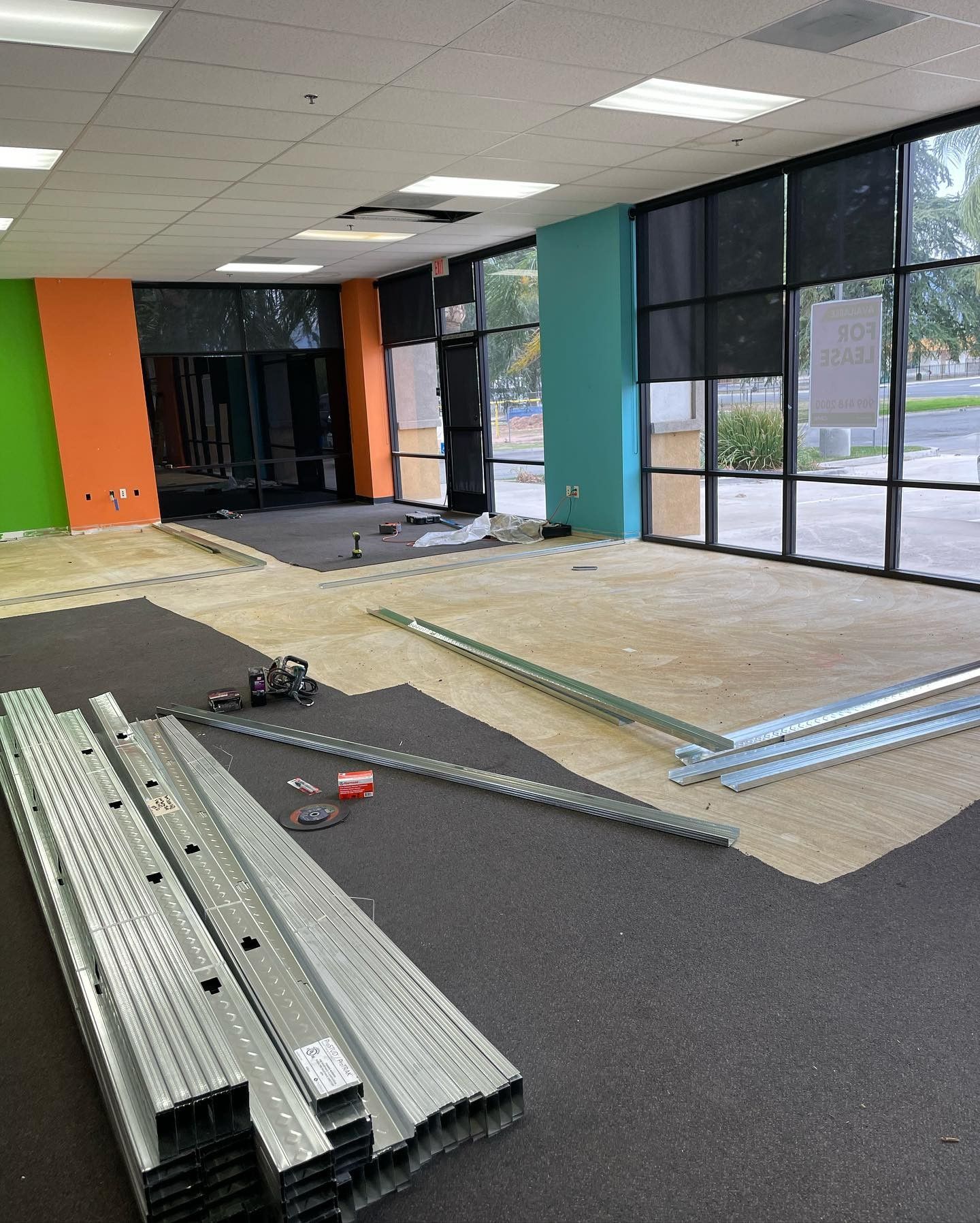 A large room with a lot of windows and a lot of pieces of metal on the floor.