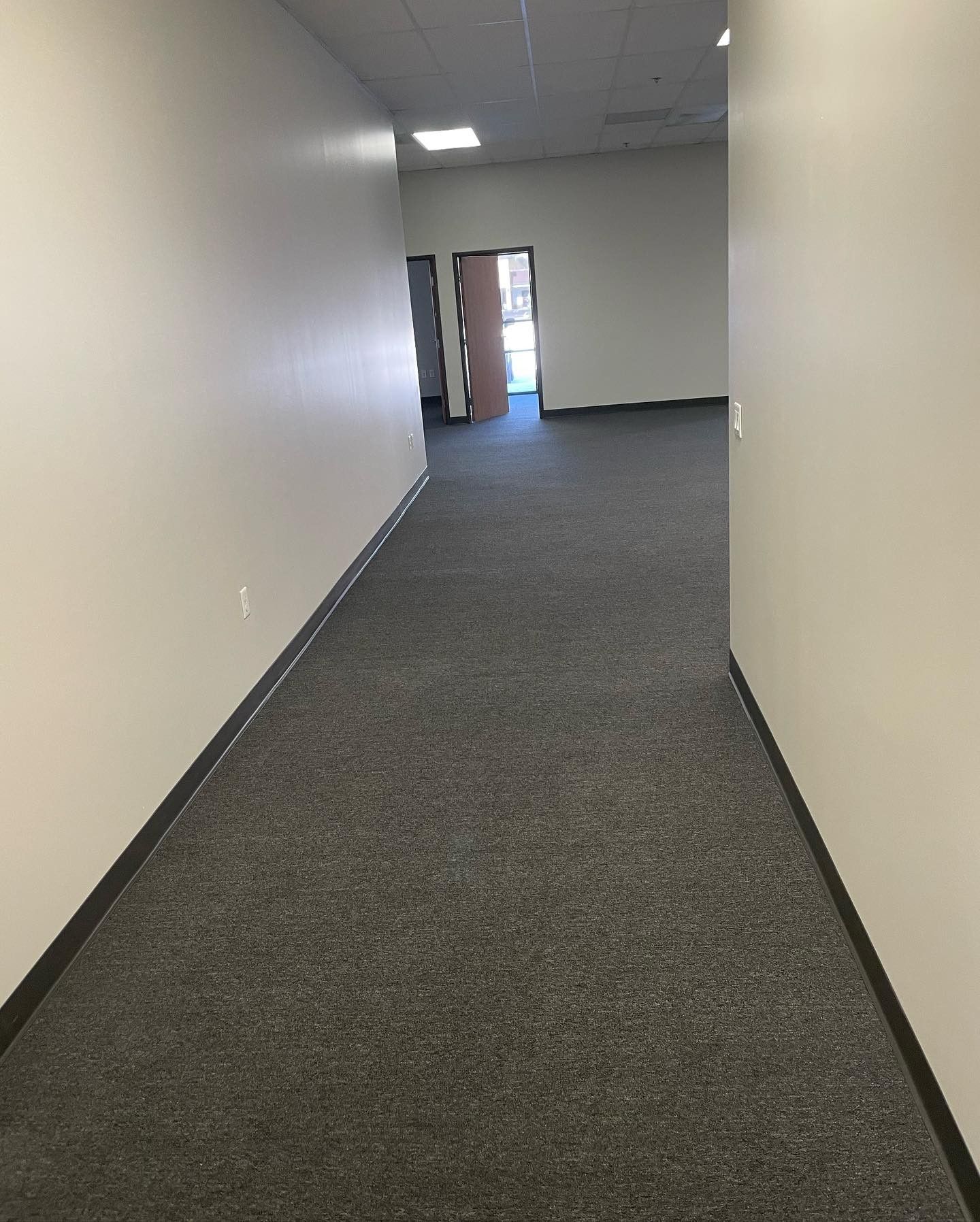 A long hallway with a carpeted floor and white walls.