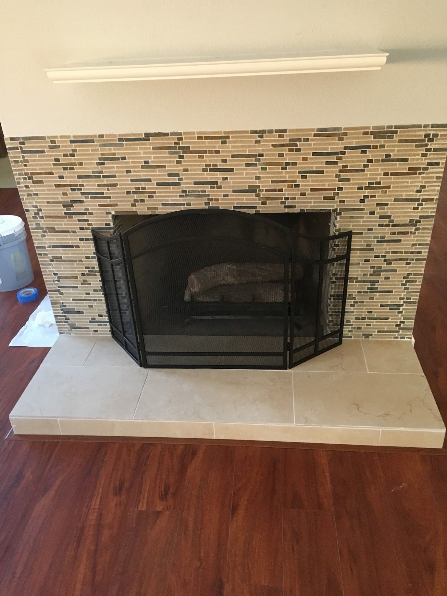 A fireplace with a screen and a wooden floor in a living room.