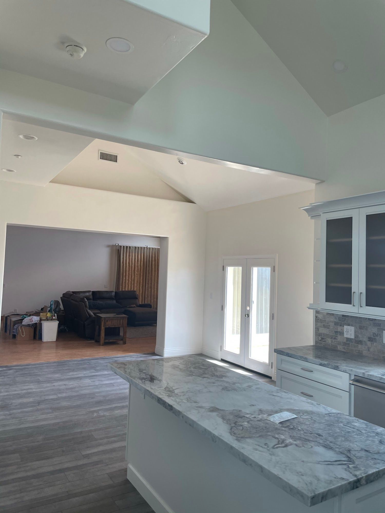 A kitchen with marble counter tops and a living room in the background.