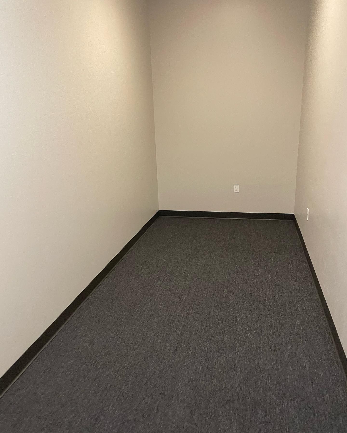 An empty room with a carpeted floor and white walls.