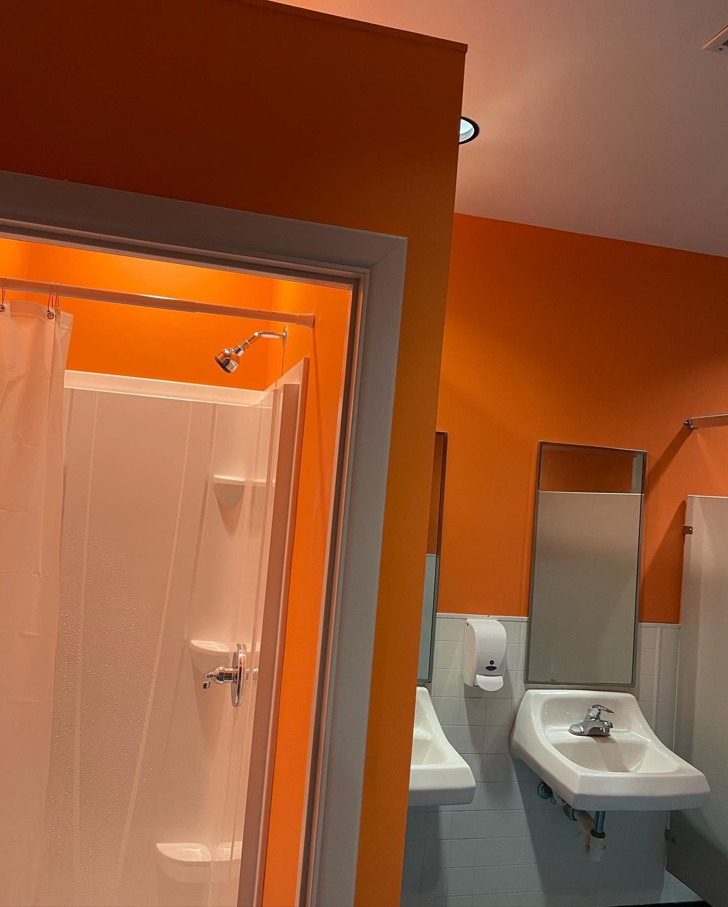 A bathroom with orange walls and a sink and shower