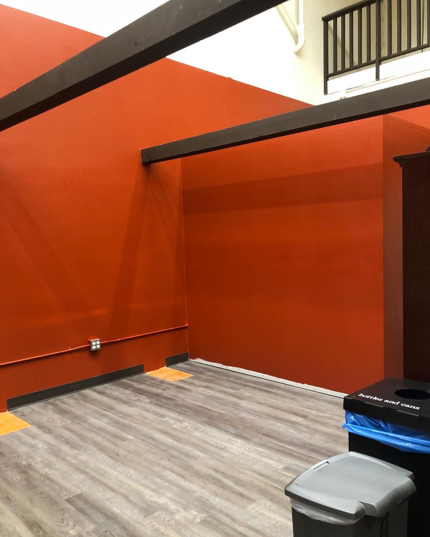 An empty room with red walls and a trash can