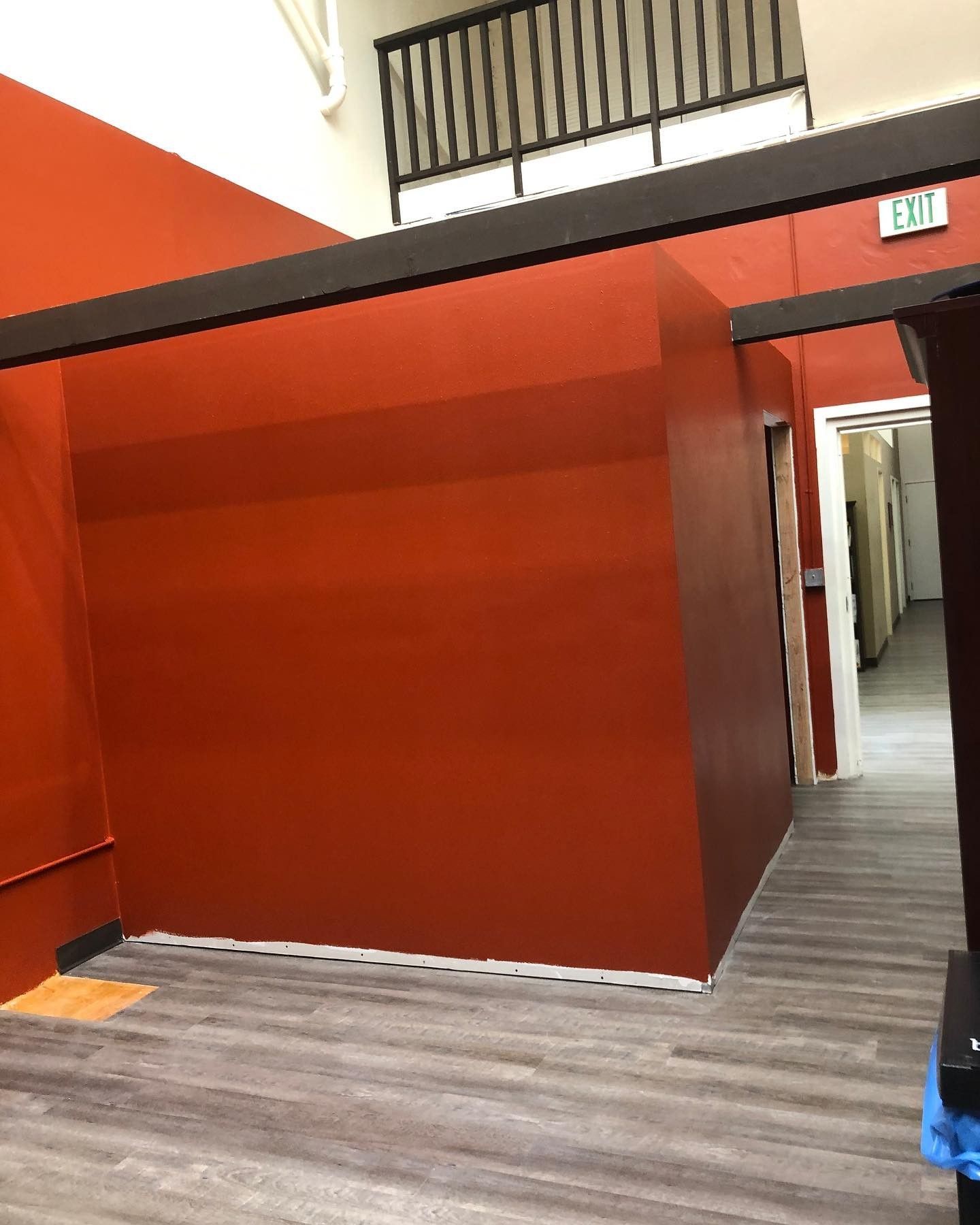 An empty room with red walls and a wooden floor.