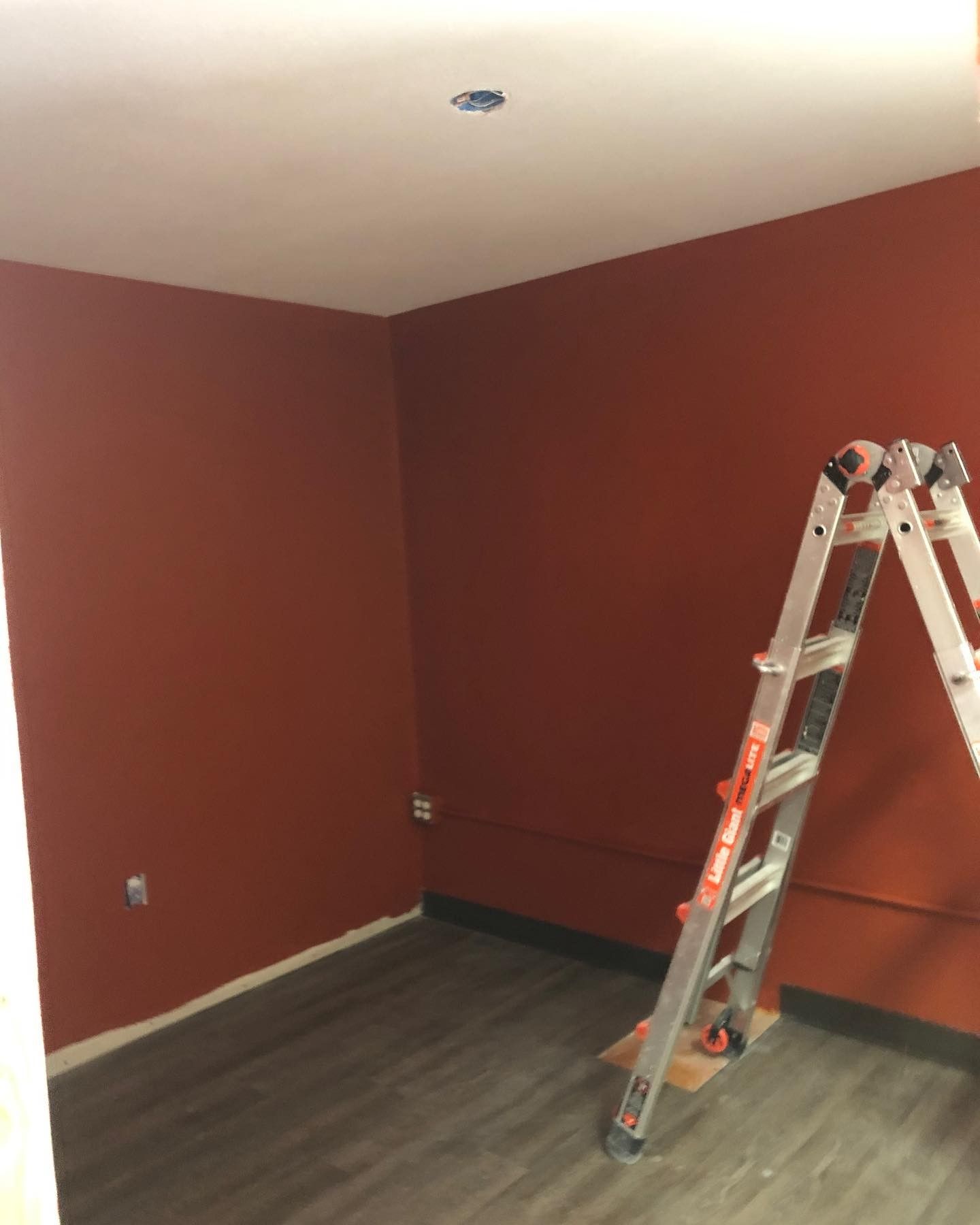 An empty room with red walls and a ladder on the floor