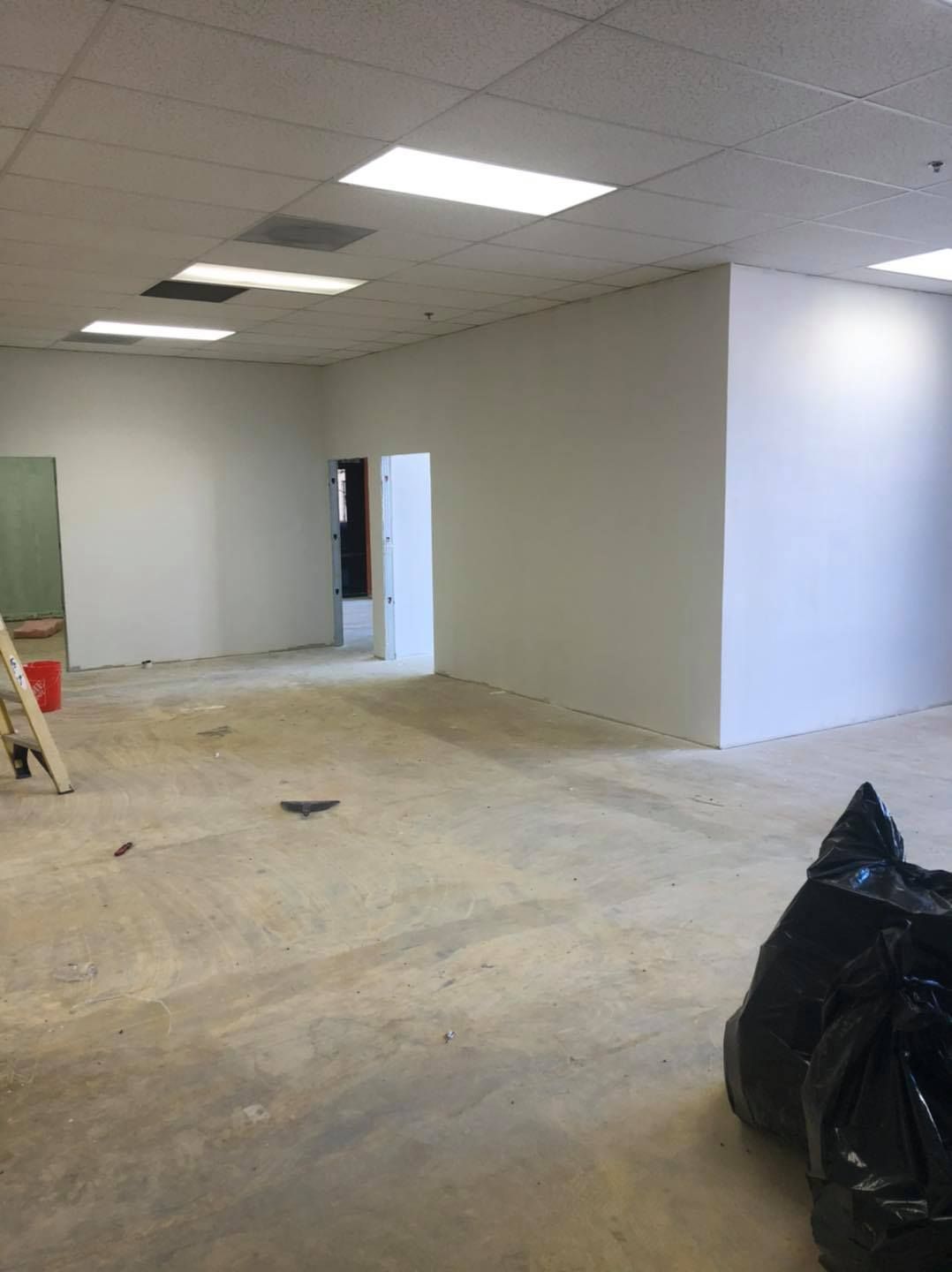 A large empty room with white walls and a black bag on the floor.