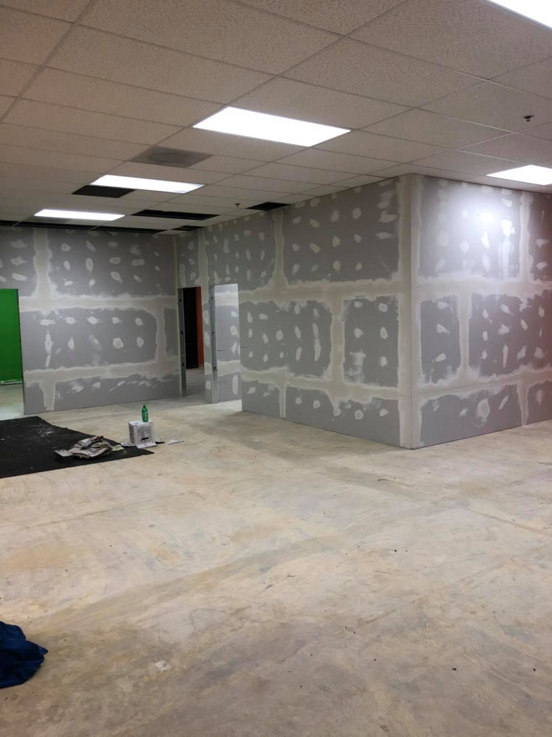 An empty room with drywall walls and a green screen.