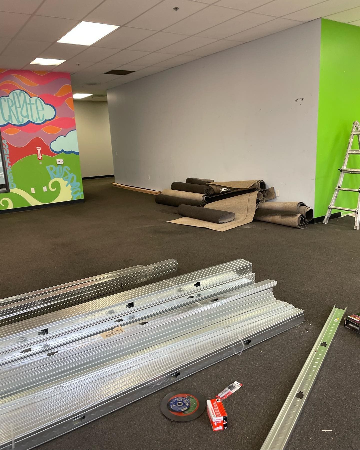 A room with a ladder and a tape measure on the floor.