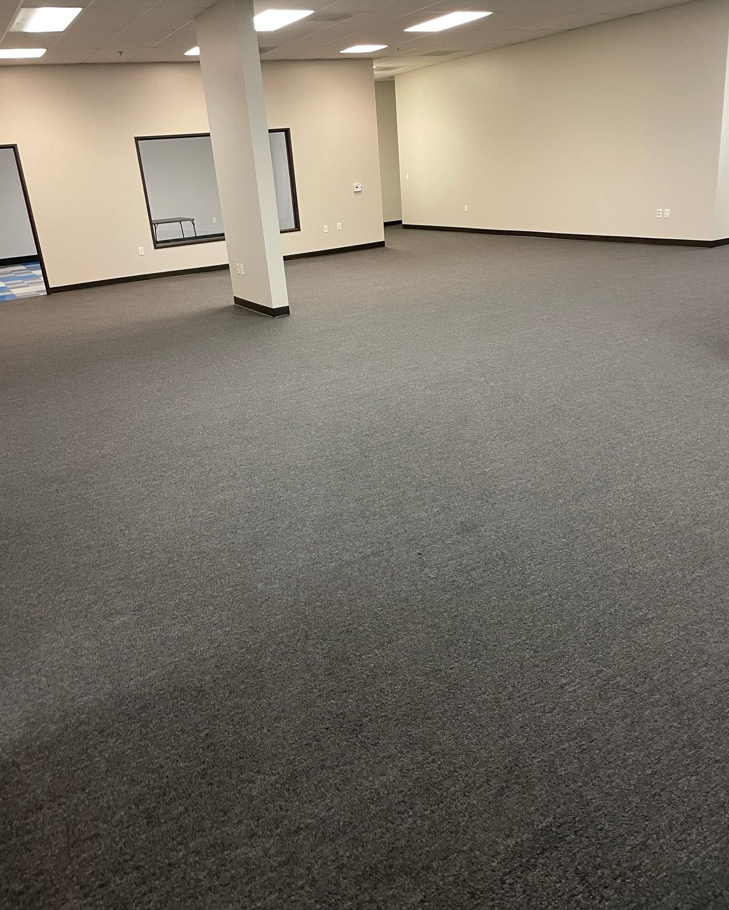 A large empty room with a gray carpet and white walls.