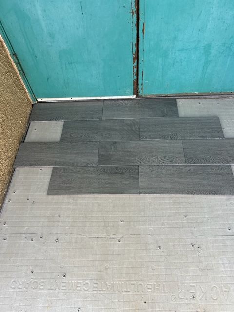 Gray planks installed on a light gray cement board, under a teal metal sheet.